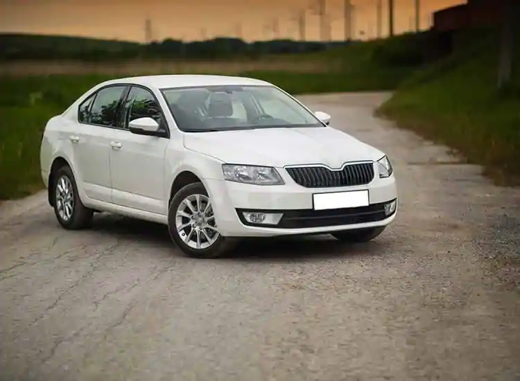 A taxi cab parked on a street at night, illuminated by streetlights and surrounded by other parked cars.